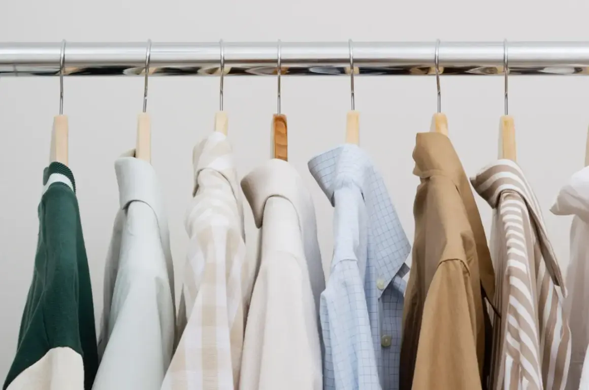 Eine Auswahl an Hemden und einem grünen Pullover für einen stilvollen **capsule wardrobe mann**.