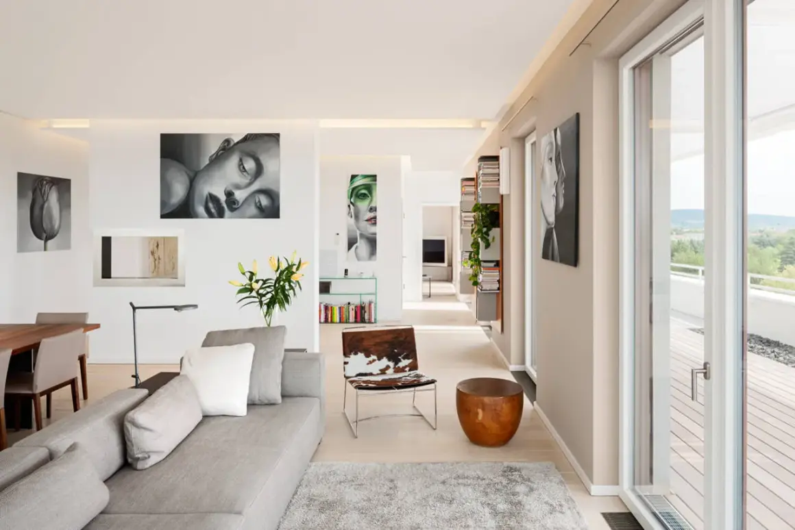 Modernes Wohnzimmer mit Kunstwerken an der wand beige streichen. Graues Sofa, Holztisch, Tierfell-Sessel und Bücherregale.