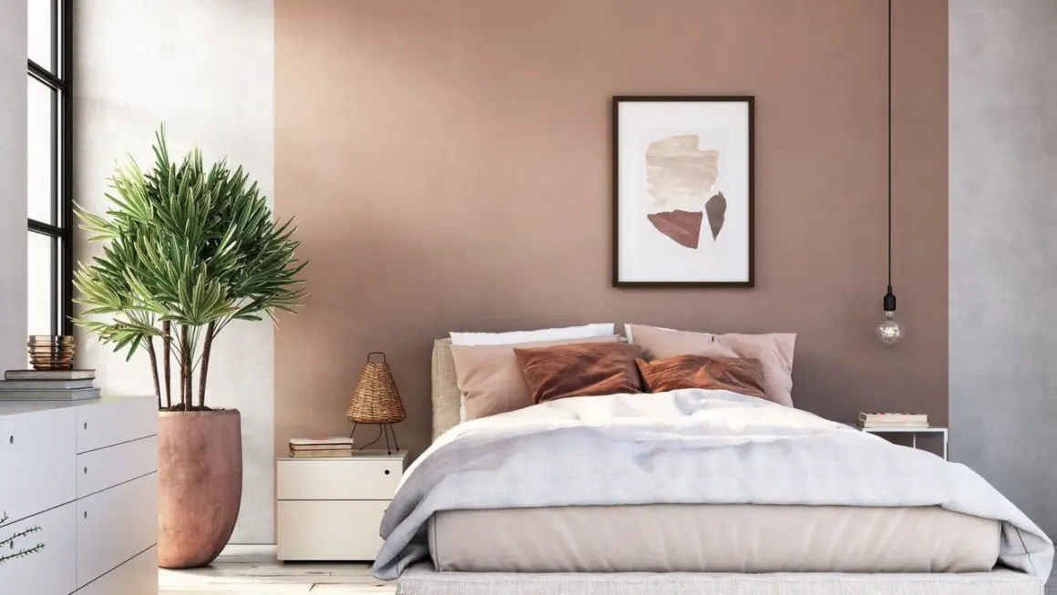 Sanfte Rosatöne und erdige Akzente für deine wandfarben schlafzimmer inspiration. Ein gemütliches Bett mit vielen Kissen und eine grüne Pflanze schaffen Wohlfühlatmosphäre.