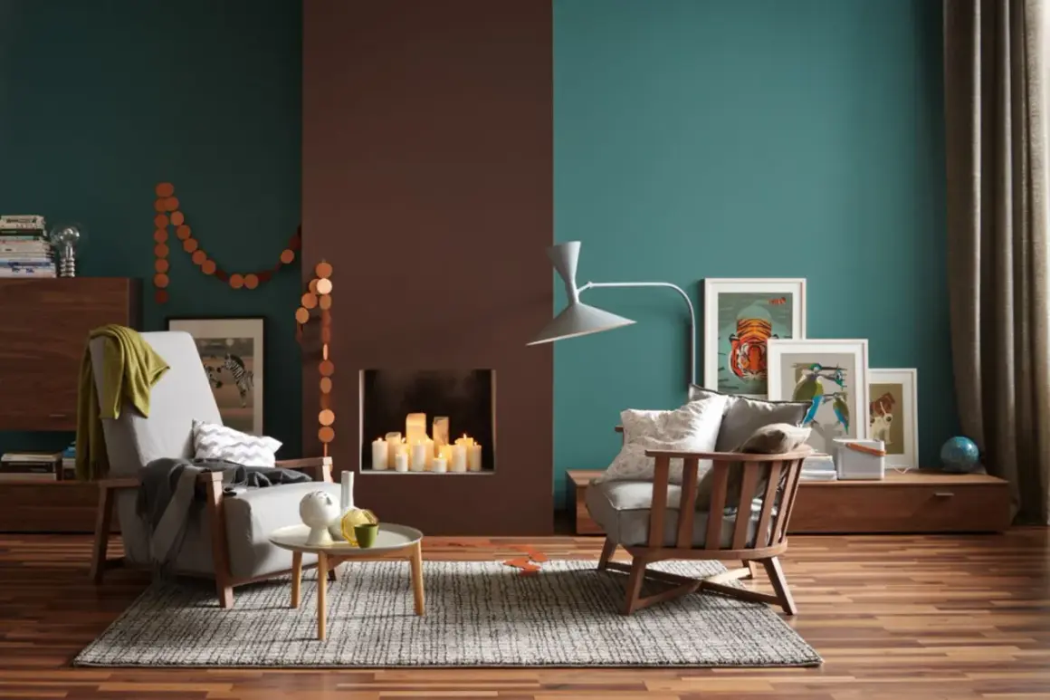 Gemütliches Wohnzimmer mit Kamin, Kerzen und Kunstwerken an den Wänden. Die Wandfarben in Petrol und Braun sind beliebte Wandfarben für ein warmes Ambiente.