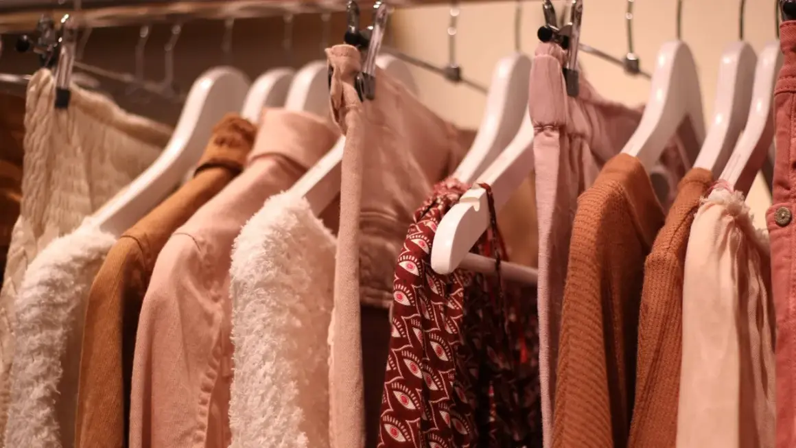 Kleiderbügel mit Kleidung in sanften Erdtönen. Ein Hauch von mode der zukunft in den Texturen und Schnitten.