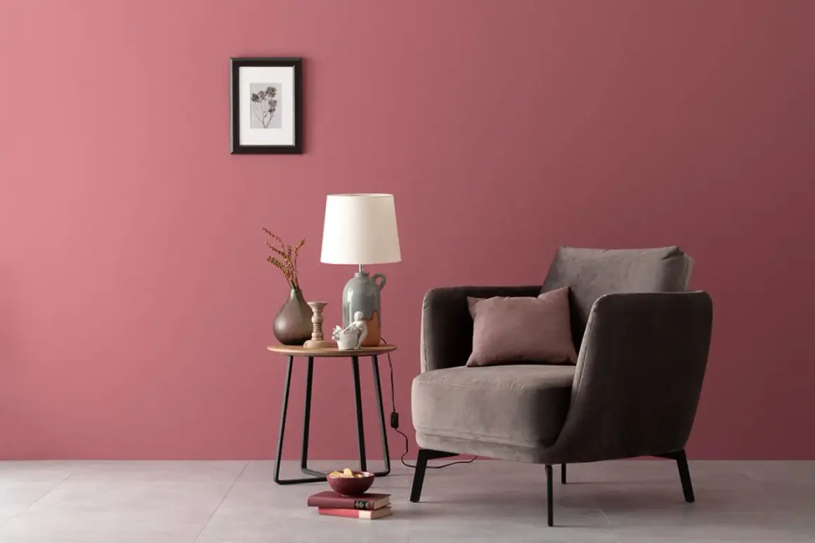 Gemütliche Ecke mit einem Sessel und Beistelltisch. Die Wand in einem warmen, englischen Rosenrot kombiniert mit dunklen Möbeln und Deko.