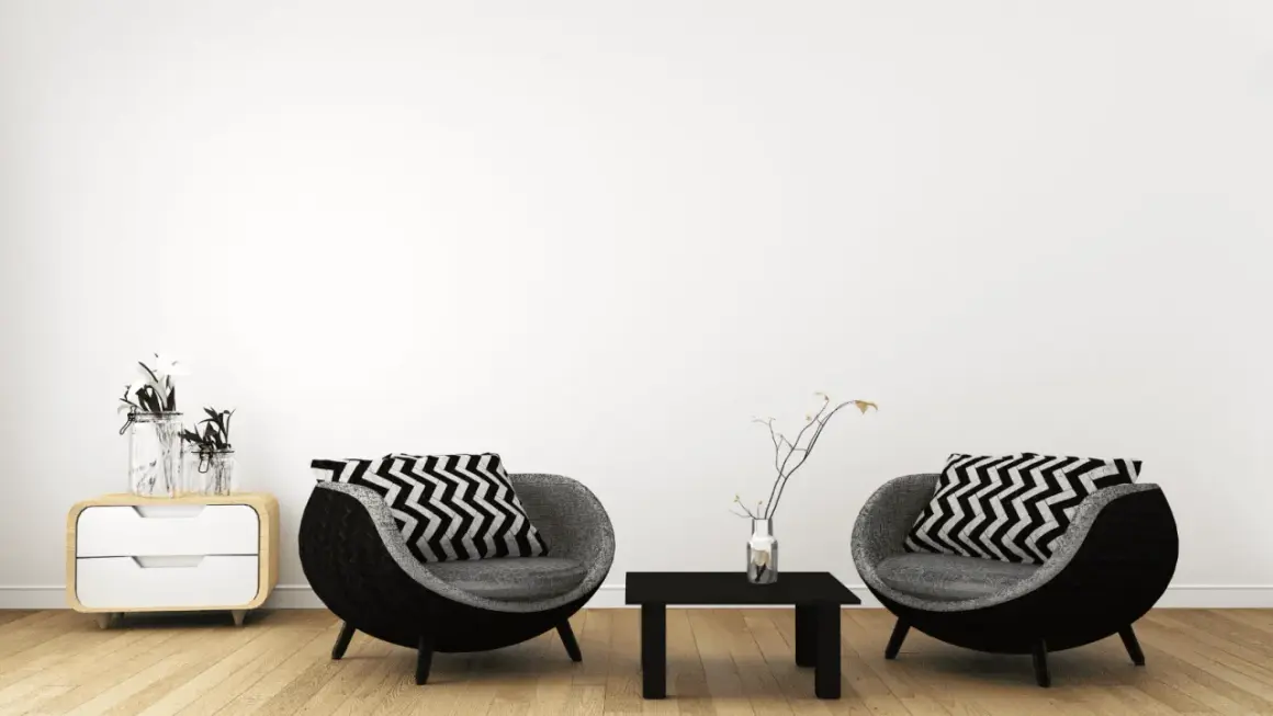 Zwei runde Sessel mit Zickzackkissen, ein kleiner Tisch und ein Nachttisch mit Vasen – ein Einblick in minimalistisch leben erfahrungen.
