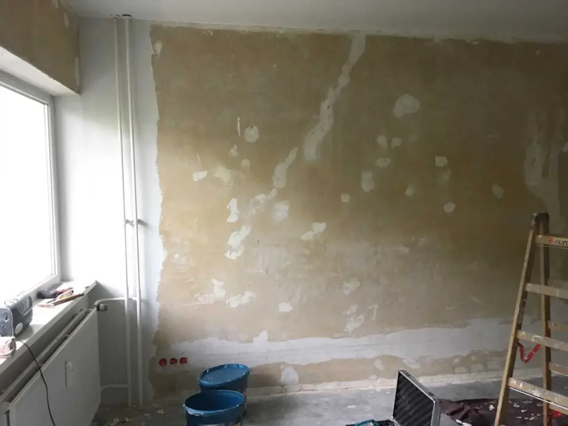 Vorbereitung für das selbst tapezieren: Wand ist vorbereitet, Werkzeug und Eimer stehen bereit.