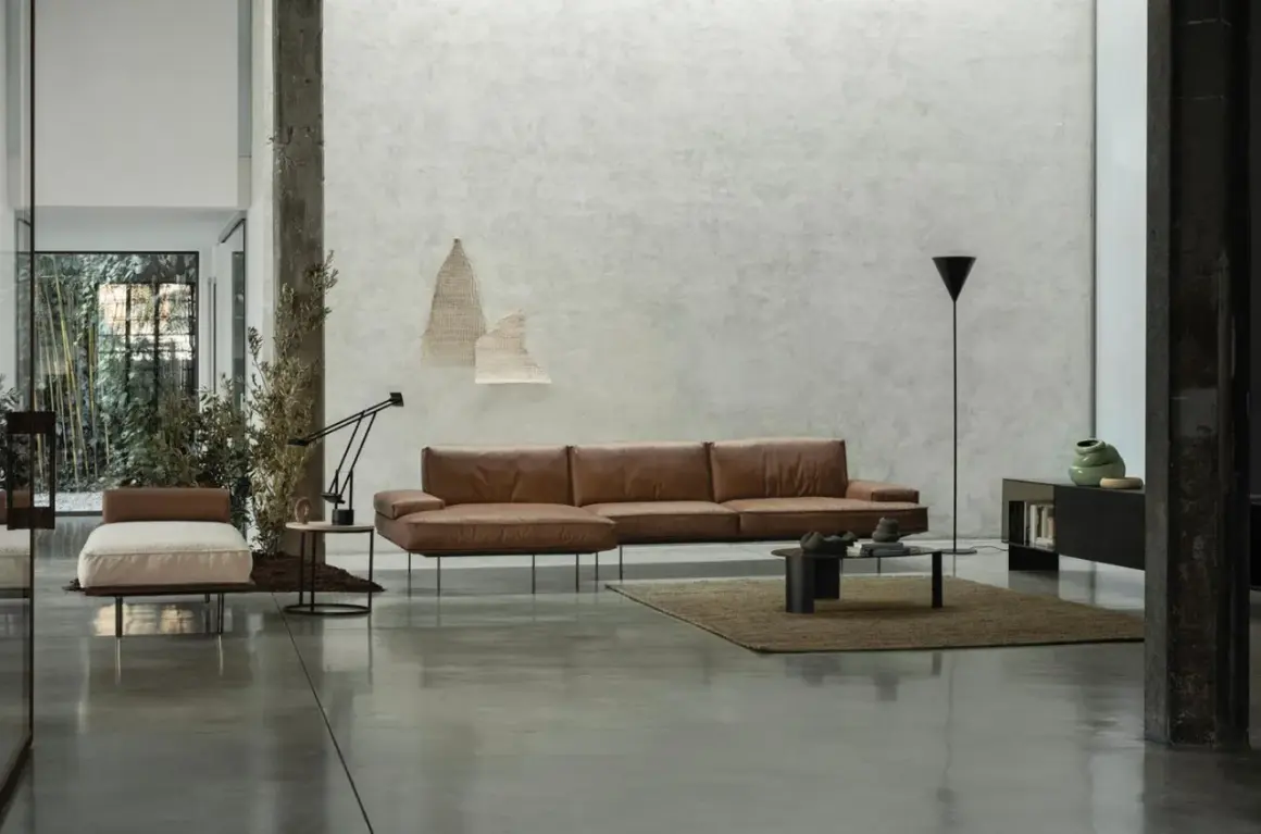 Modernes Wohnzimmer mit Ledersofa, Couchtisch und einem dunklen Boden, der die minimalistische Einrichtung unterstreicht.