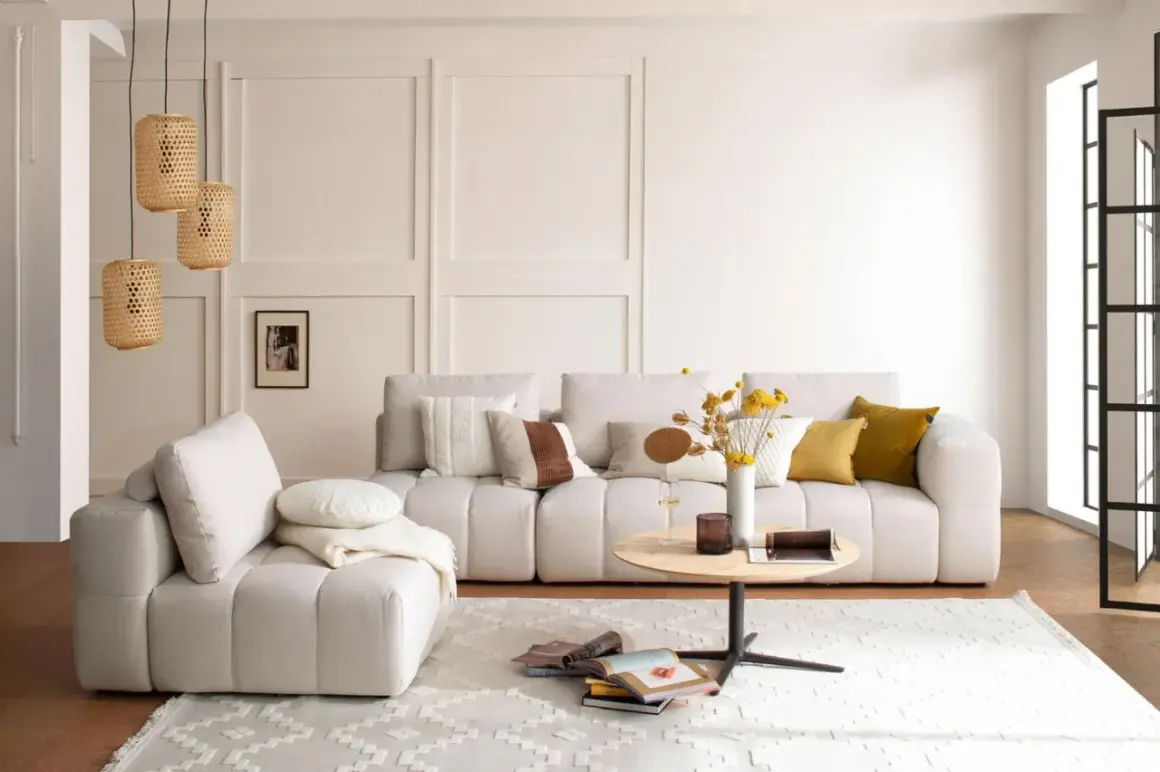Gemütliches Wohnzimmer mit beiger Couch, Kissen, Couchtisch und Körblampen. Perfekt für slow living einrichtung.
