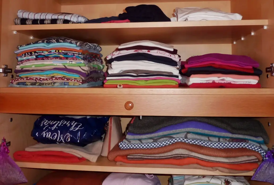 Ordentlich gestapelte Kleidung in einem Schrank. Zeit zum **Kleidung aussortieren** und Platz schaffen für Neues.