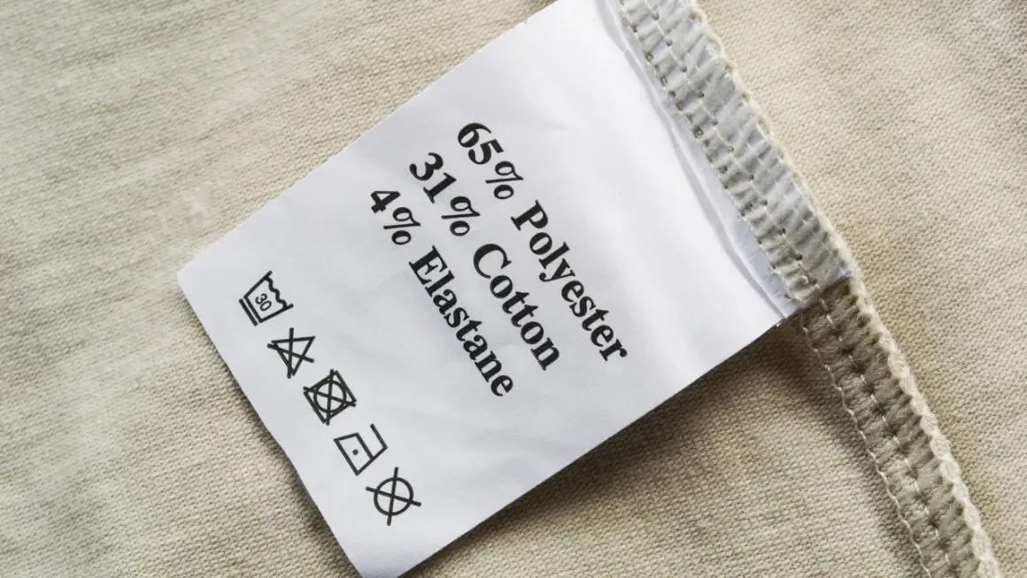 Pflegeetikett mit Materialzusammensetzung: 65% Polyester, 31% Baumwolle, 4% Elastan. Die Textilkette ist gut lesbar.