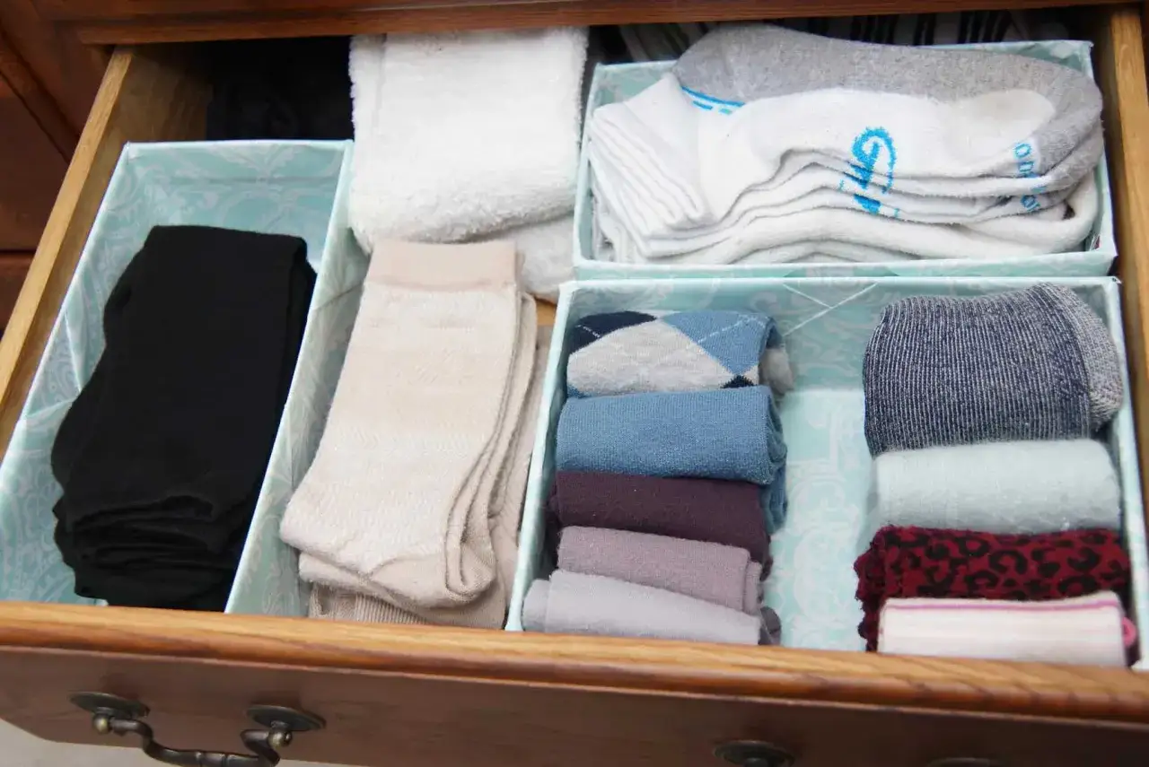 Offene Schublade mit ordentlich gefalteten Socken in verschiedenen Farben und Mustern. Hier sieht man, wie viele socken man braucht, um den Überblick zu behalten.