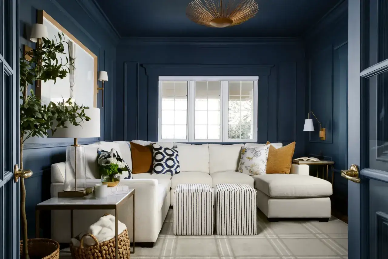 Gem&uuml;tliches Wohnzimmer mit einem wei&szlig;en Ecksofa, Akzentkissen in blau nuancen und einem Teppich.