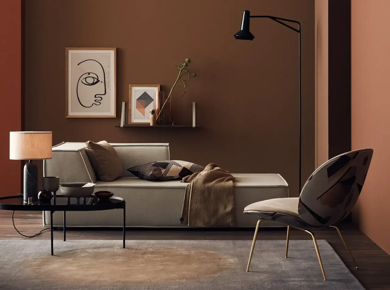 Gemütliches Wohnzimmer mit einer braunen Wand, einem Sofa, einem Sessel und einem Couchtisch.