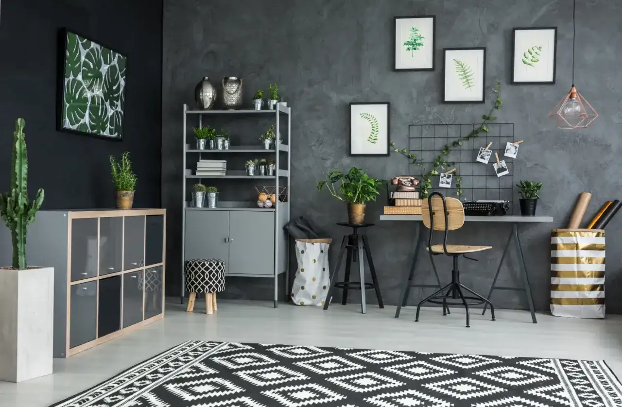 Ein Arbeitsplatz mit Pflanzen und Vintage-Elementen. Die graue Wand mit Struktur ist ein toller Hintergrund, aber warum Tapete? Ein Bild mit Monstera-Blättern und ein Teppich mit geometrischem Muster.