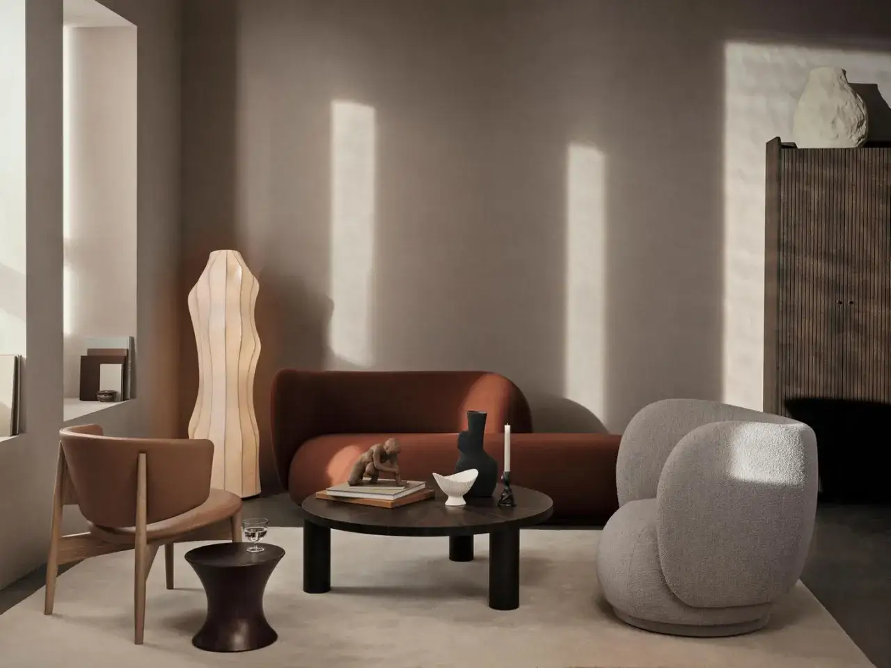Ein Wohnzimmer mit einem braunen Sofa, einem Sessel, einem Couchtisch und einer Stehlampe. Das warme Braun des Sofas l&auml;dt zum Entspannen ein.