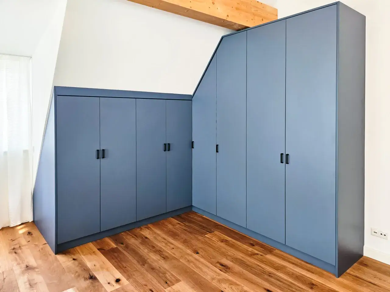 Große, blaue Einbauschränke in einem modernen Raum mit Holzboden. Sie bieten viel Stauraum, was bei der Kleidung und dem Konsum relevant ist, wenn man Statistiken zur Aufbewahrung betrachtet.