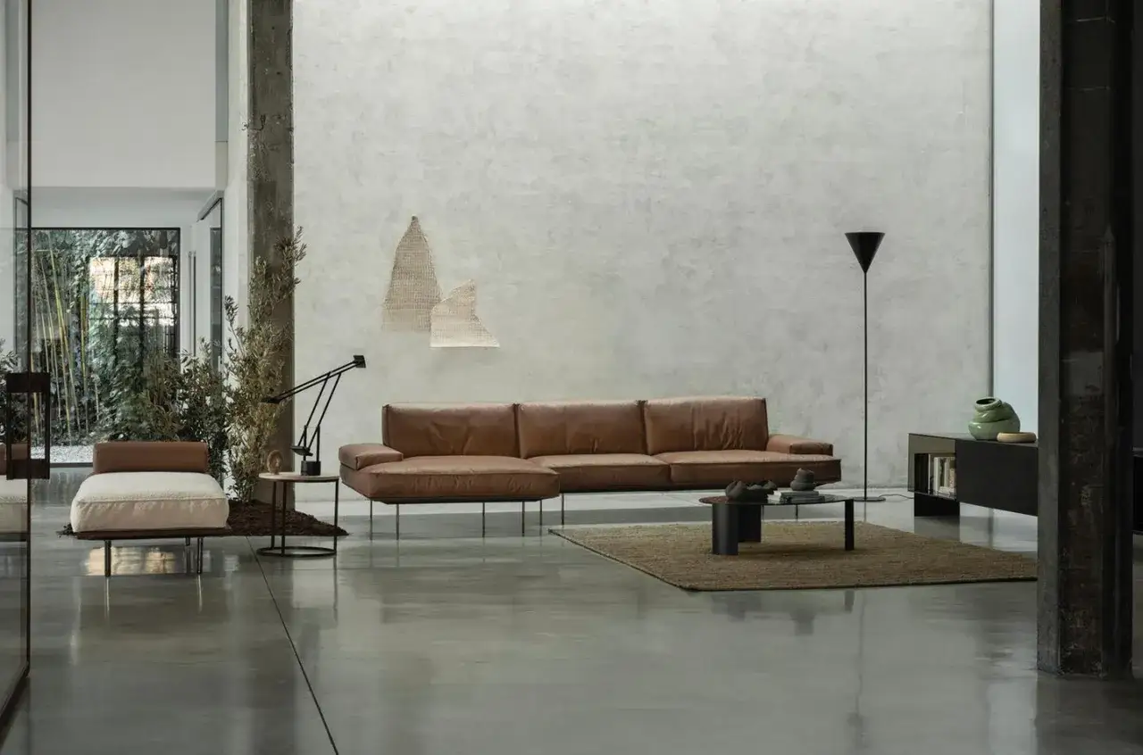 Modernes Wohnzimmer mit Ledercouch, Kunst und einem dunklen Boden, der die minimalistische Einrichtung unterstreicht.