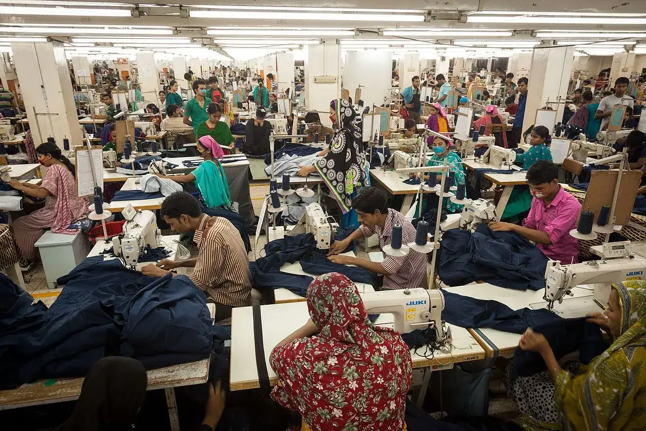 Menschen arbeiten in einer Textilfabrik, ein Beispiel für die Nachteile von Fast Fashion: Ausbeutung und schlechte Arbeitsbedingungen.