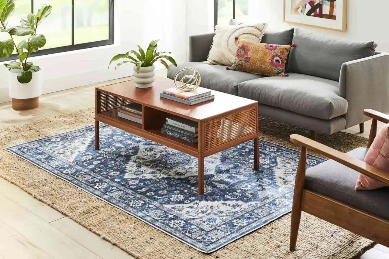 Mehrere Teppiche in einem Raum: Ein rustikaler Jute-Teppich bildet die Basis für einen blauen Vintage-Teppich mit orientalischem Muster.