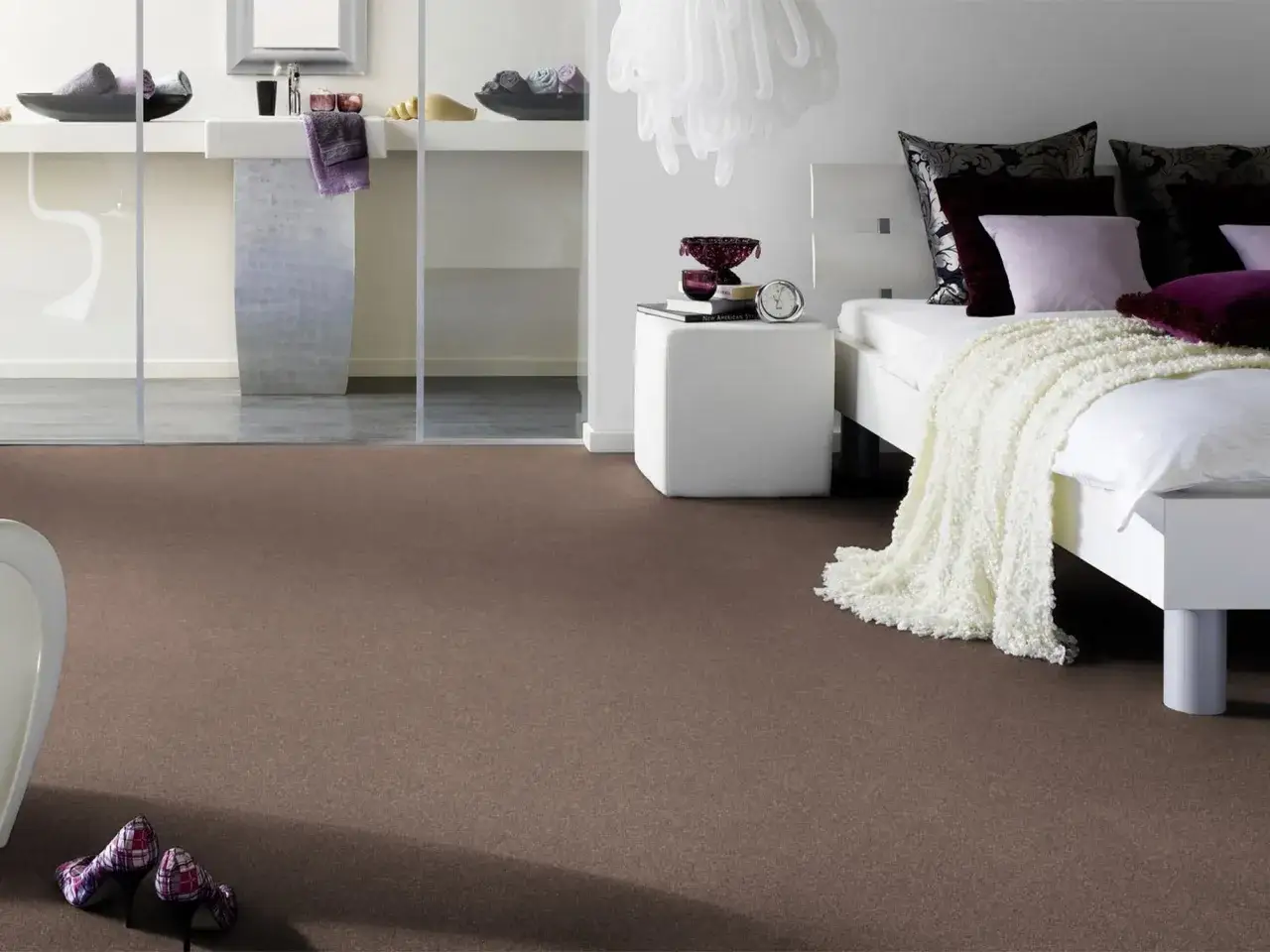 Ein gemütlicher Teppich bedeckt das ganze Zimmer, von der modernen Badewanne bis zum eleganten Bett mit vielen Kissen.