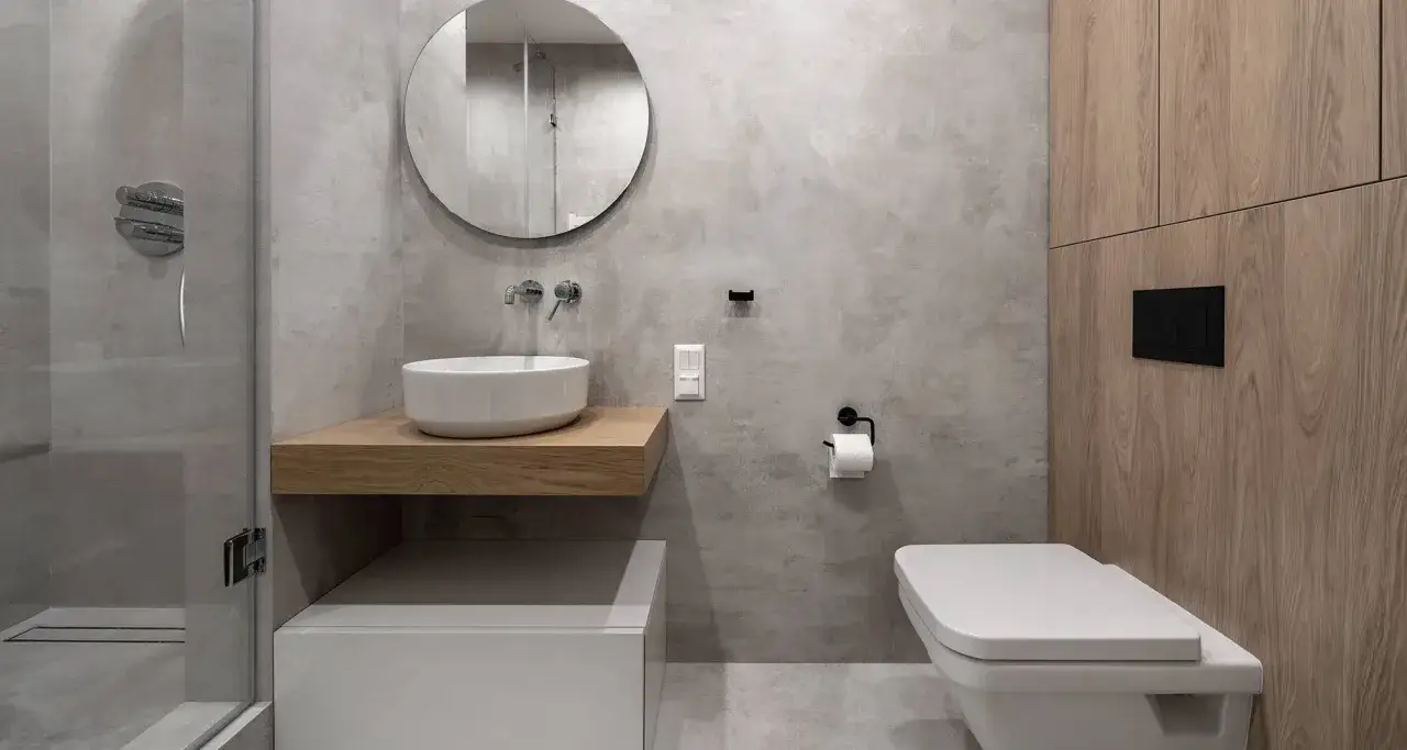 Modernes, fugenloses Bad mit Dusche, Waschbecken auf Holzablage, WC und Holzelementen. Minimalistisch und stilvoll.