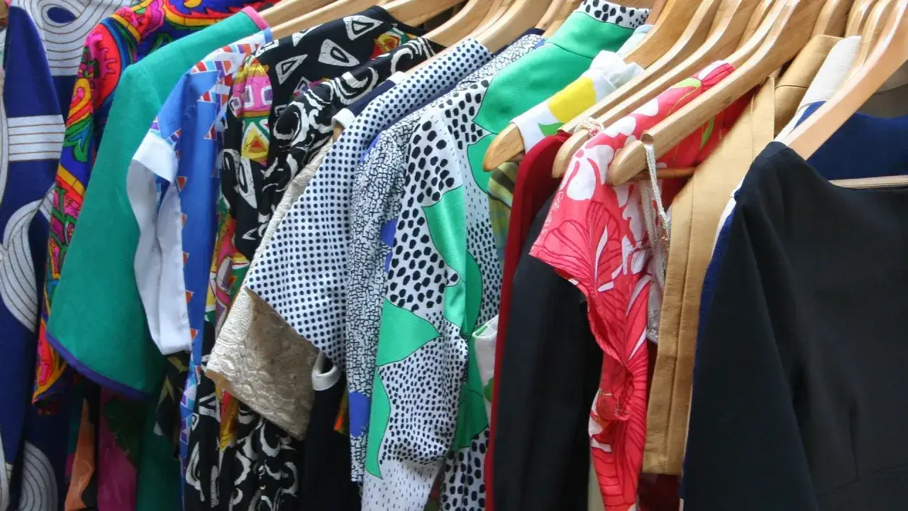 Bunte Kleider auf Kleiderbügeln. Viele Marken produzieren nicht fair, aber diese Vielfalt lädt zum Nachdenken über bewussten Konsum ein.