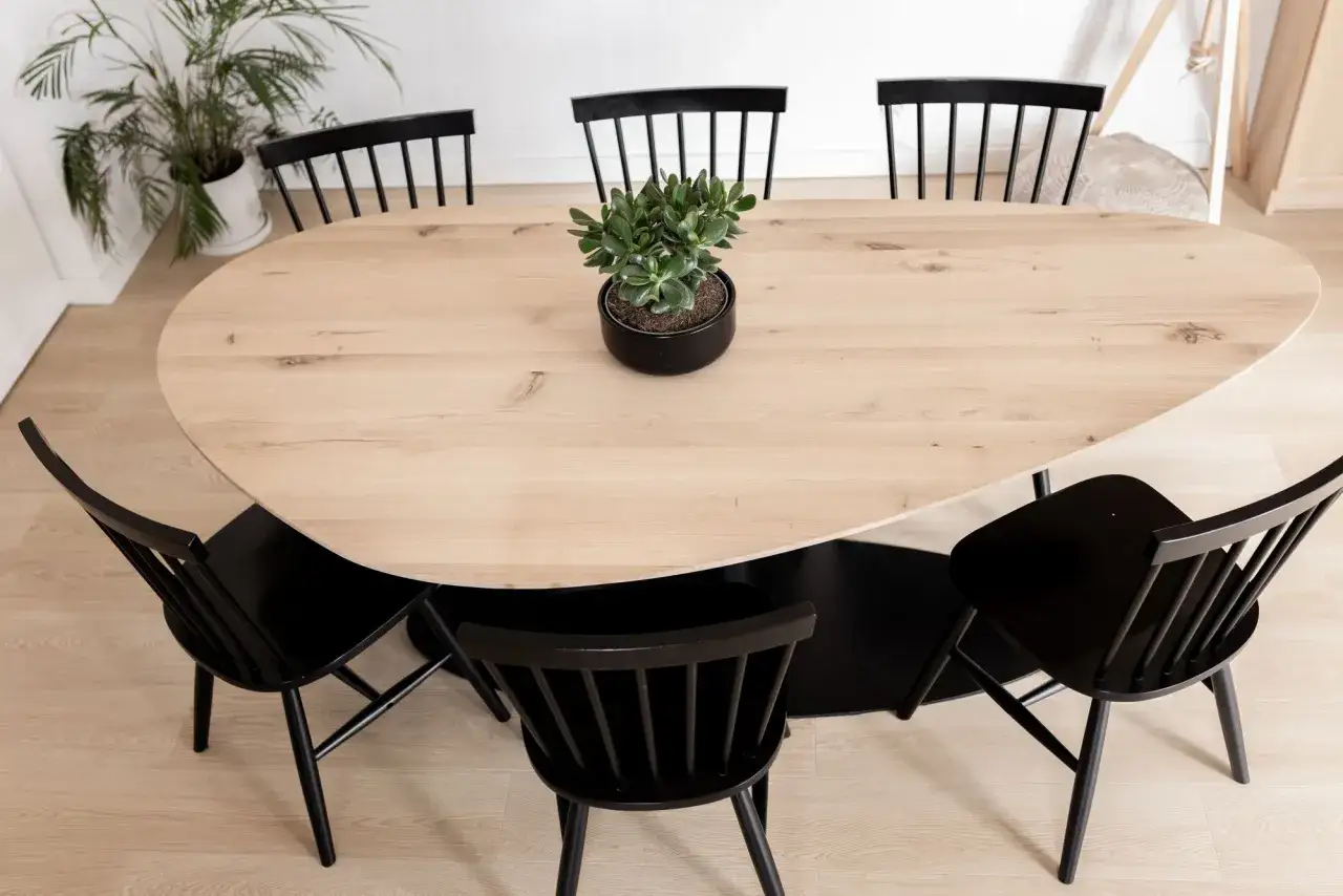 Moderner Esstisch aus hellem Holz mit schwarzen St&uuml;hlen und einer gr&uuml;nen Pflanze in der Mitte. Perfekte esstisch inspo f&uuml;r ein stilvolles Zuhause.