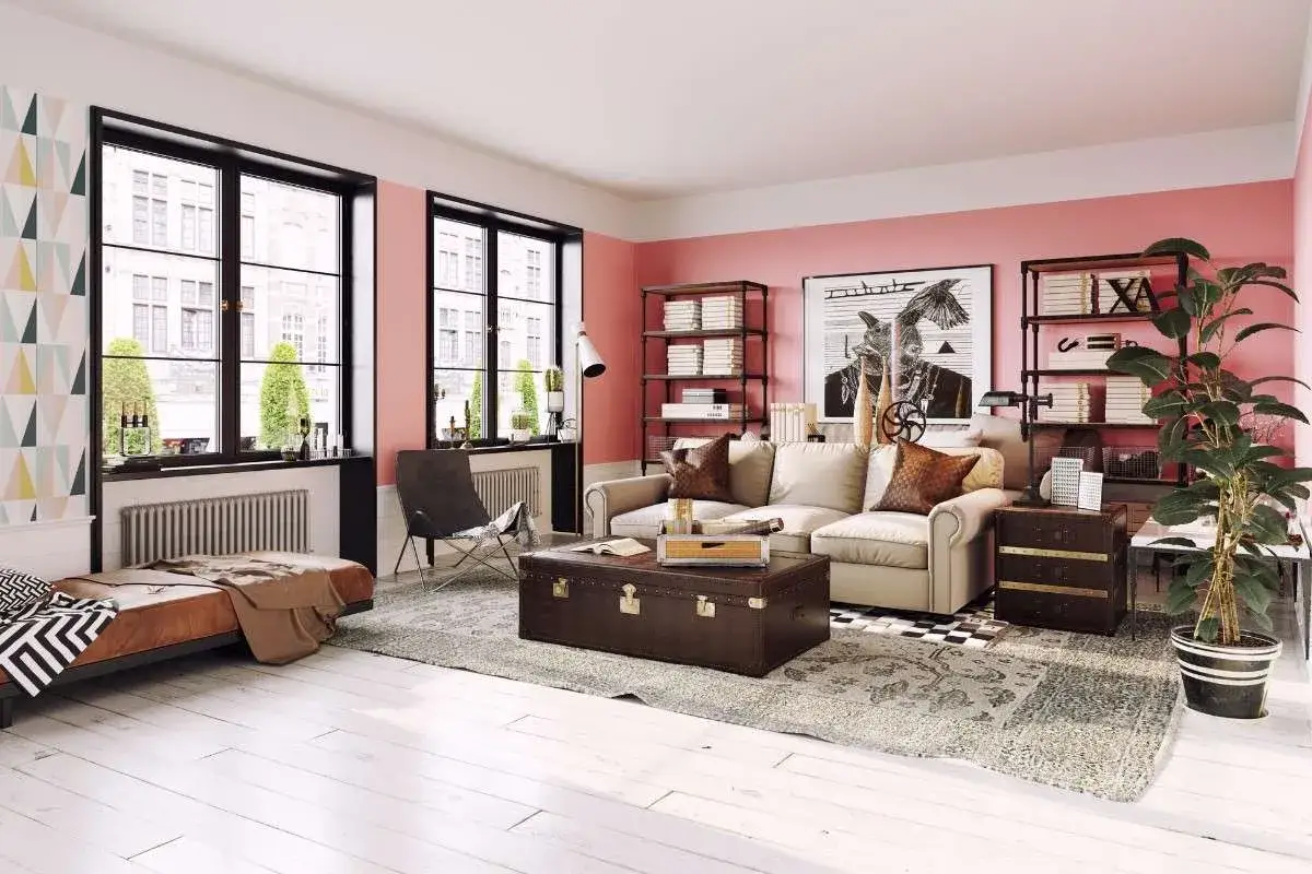 Gemütliches Wohnzimmer mit rosa Wand, bequemer Couch, Vintage-Truhe und viel Licht durch große Fenster.