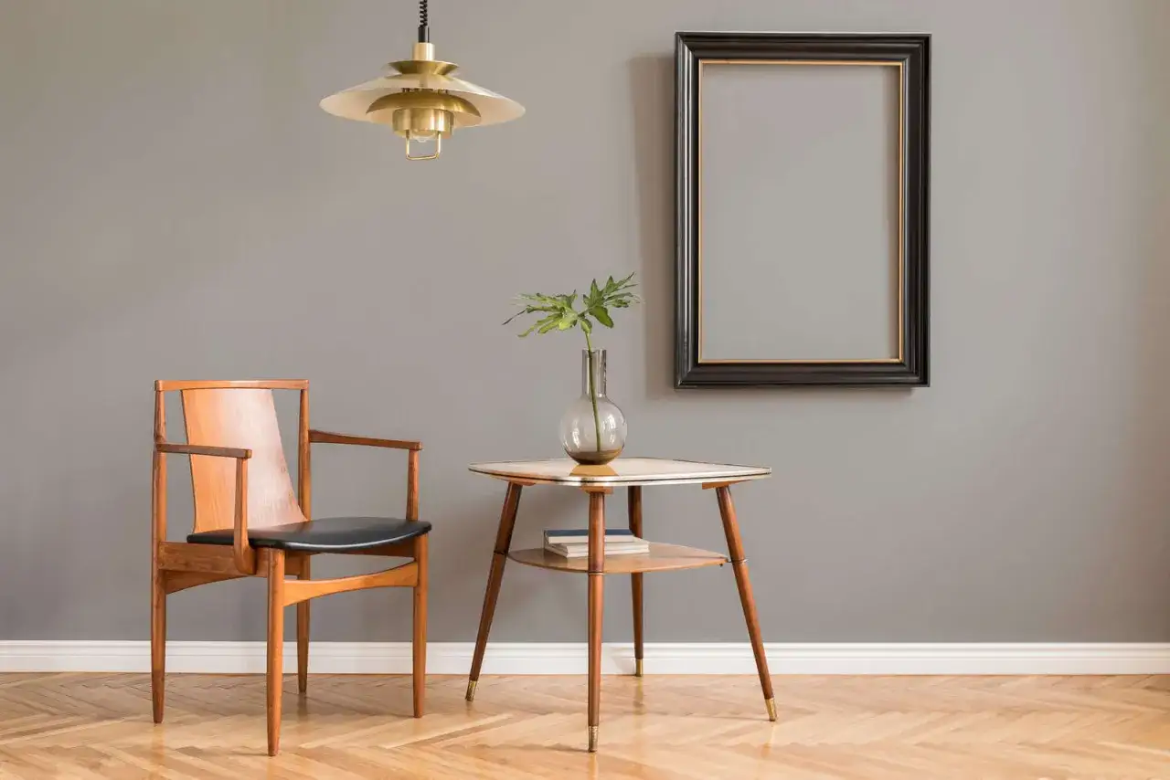 Ein Sessel aus Holz und Leder steht neben einem Beistelltisch mit Vase. Welche Farbe passt zu seidengrau? Dieses Ambiente zeigt warme Holztöne.