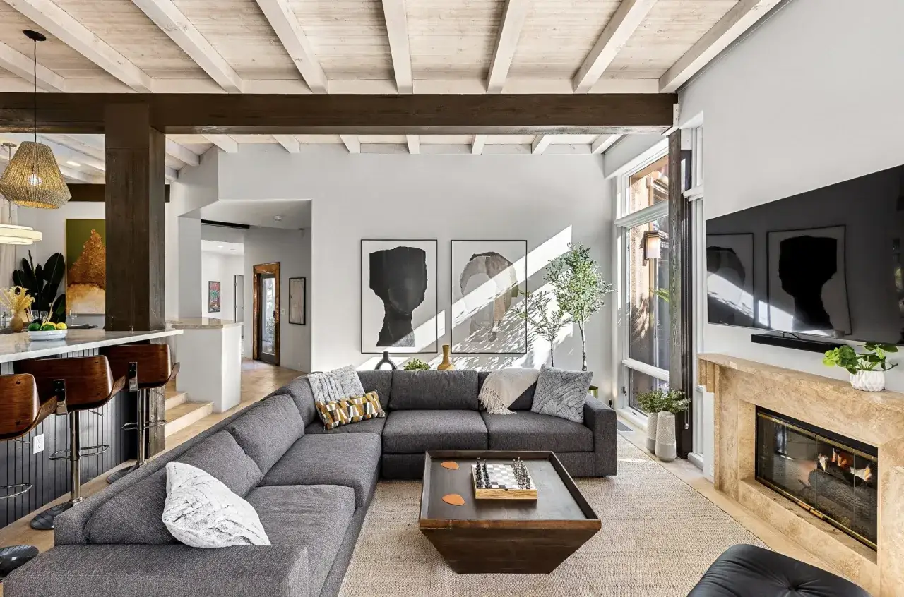 Modernes Wohnzimmer mit beigem Teppich, grauem Ecksofa, Schachbrett-Couchtisch und Kamin &ndash; ein Beispiel f&uuml;r neue Wohntrends.