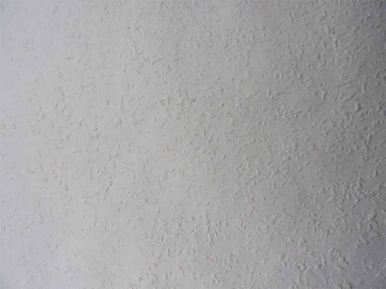 Eine wei&szlig;e Raufasertapete mit feiner K&ouml;rnung, die verschiedene Arten von Raufasertapeten zeigt.