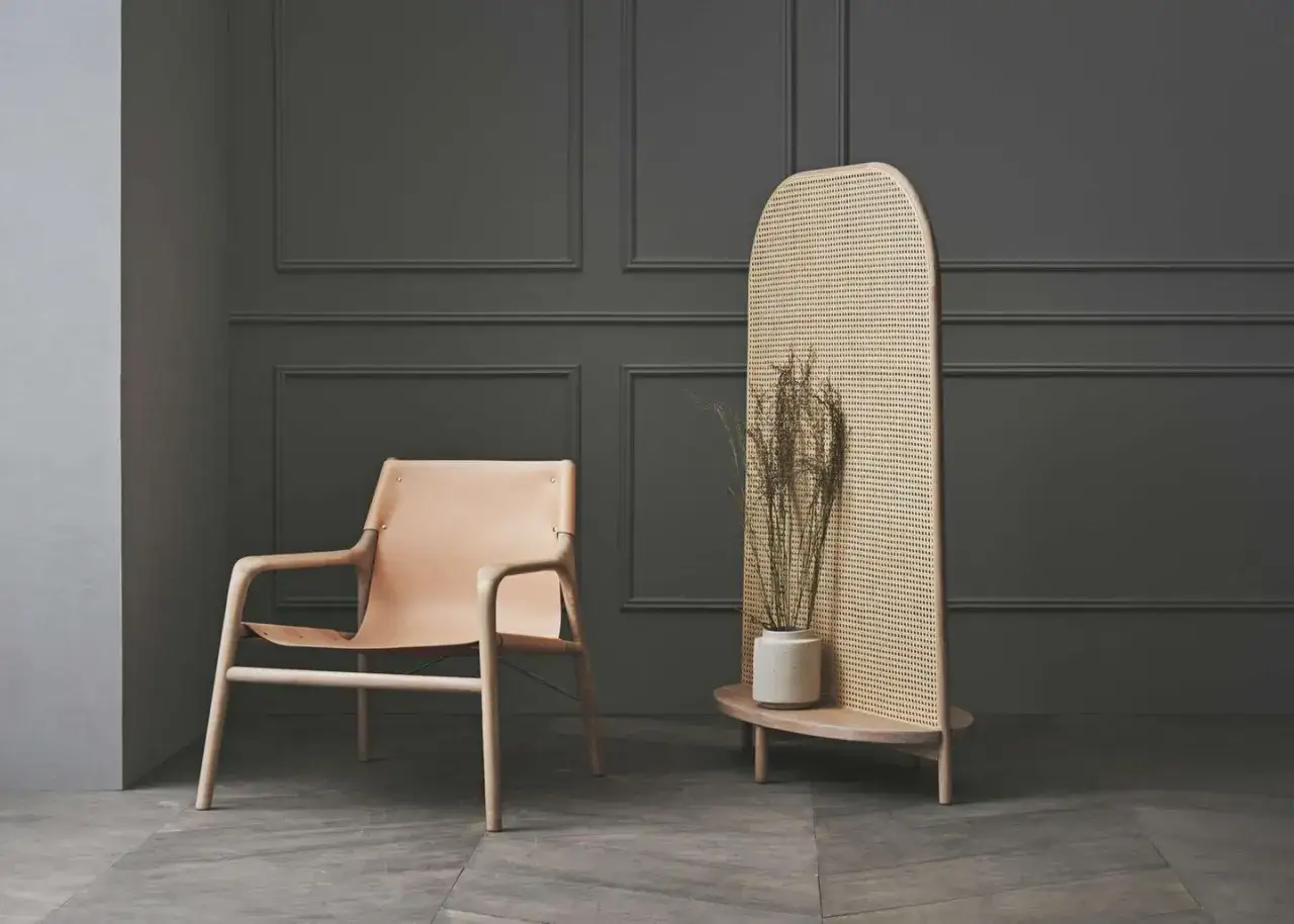 Ein Ledersessel und ein Rattan-Raumteiler mit Trockenblumen – ein trendiger Blickfang im minimalistischen Interieur.