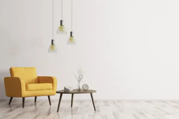 Ein gelber Sessel, ein kleiner Tisch mit Büchern und Deko, drei Hängelampen – ein Raum im extremen Minimalismus.