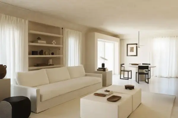 Minimalist Wohnzimmer mit weißem Sofa, Beistelltischen und Essbereich. Ein Beispiel für einen modernen Lebensstil, der Ruhe und Ordnung ausstrahlt.