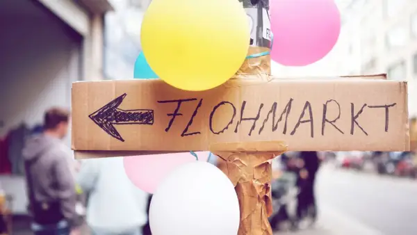 Bunte Ballons und ein handgemalter Pfeil auf Pappe weisen den Weg zum Flohmarkt. Perfekt für deine Flohmarkt-Checkliste!