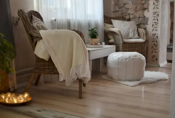 Gemütliches hygge style wohnzimmer mit Korbstühlen, weichen Decken und warmem Licht.