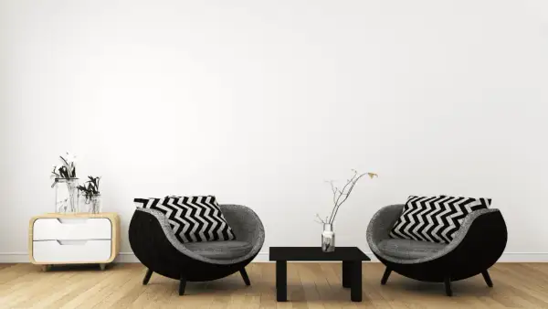 Zwei runde Sessel mit Zickzackkissen, ein kleiner Tisch und ein Nachttisch mit Vasen – ein Einblick in minimalistisch leben erfahrungen.