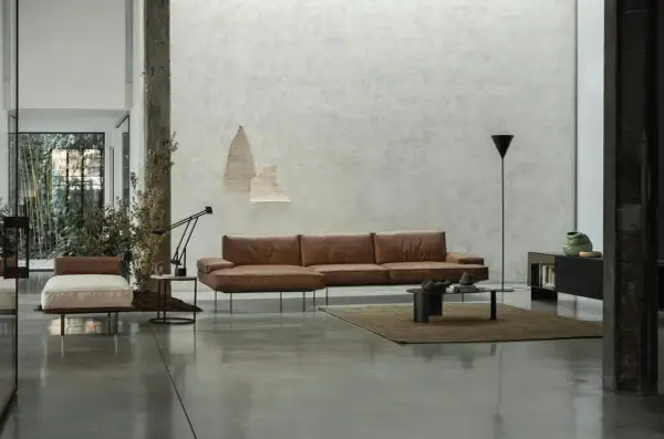 Modernes Wohnzimmer mit Ledersofa, Couchtisch und einem dunklen Boden, der die minimalistische Einrichtung unterstreicht.